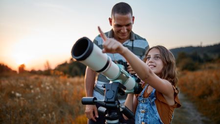 a father and daughter using a telescope