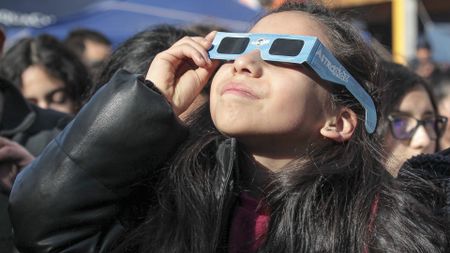 A kid is shown looking at the solar eclipse while wearing special protective glasses