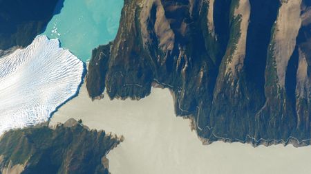 Astronaut photo of the point where a glacier, green river and blue lake meet in a valley system in Patagonia