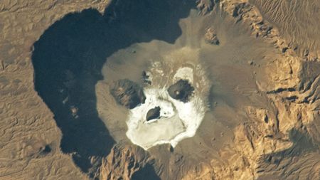 An astronaut photo of a volcanic caldera with a skull like shape